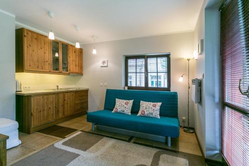 ein Wohnzimmer mit einem blauen Sofa und einer Küche in der Unterkunft Apartamenty Zakopane Droga na Bystre 4A in Zakopane