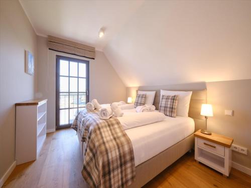 a bedroom with a large white bed with towels on it at Reetland am Meer - Luxus Reetdachvilla mit 3 Schlafzimmern, Sauna und Kamin H20 in Dranske