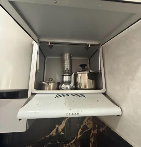 a shelf with pots and pans in a kitchen at شقق عائلية in Fnidek