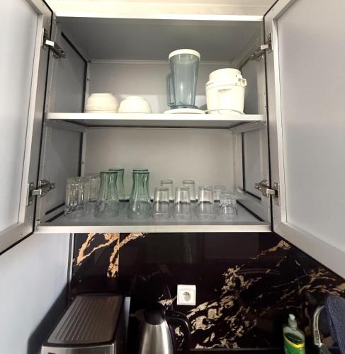 a cupboard filled with lots of glass jars and a tea kettle at شقق عائلية in Fnidek