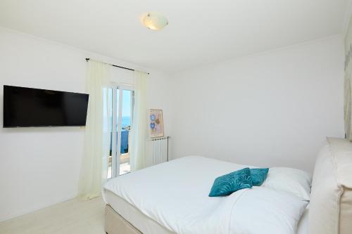 a white bedroom with a white couch and a television at Hedera Estate Hedera A54 in Mlini