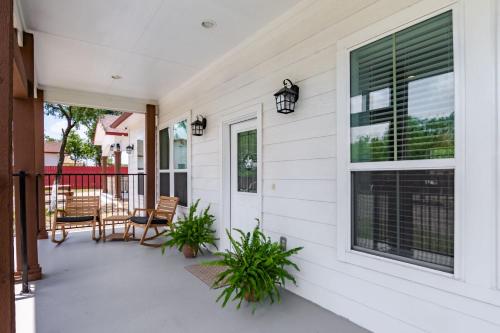 a white house with a porch with two plants at Family-Ready 4BR with Yard & Kids Playground in Cedar Creek