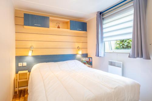 a bedroom with a white bed and a window at Camping à 300m de la plage La Pege in Saint-Hilaire-de-Riez