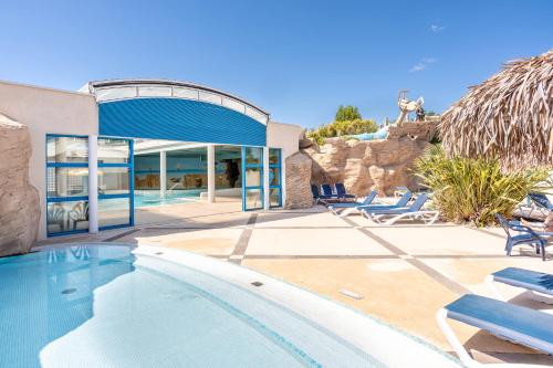une piscine avec des chaises et un bâtiment dans l'établissement Camping à 300m de la plage La Pege, à Saint-Hilaire-de-Riez