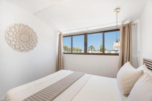 コスタ・デル・シレンチオにあるA T Suite Costa del Silencioのベッドと窓のある白い寝室