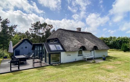 a house with a thatched roof with a deck at Hobbit Huset in Ringkøbing