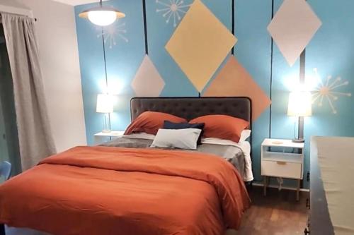 a bedroom with a bed with orange sheets and blue walls at The Mod Pod in Eugene
