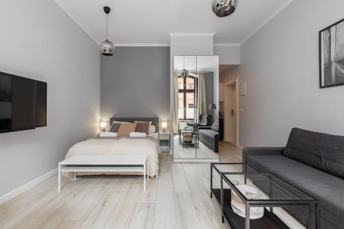 a bedroom with a bed and a living room with a couch at Good Weather Apartment in Poznań