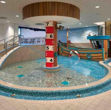 a large pool in a cruise ship with a water slide at Lighthouse Hotel & Spa in Büsum