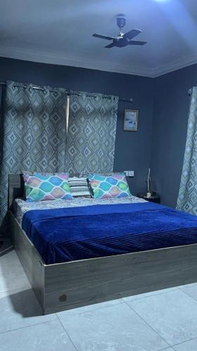a bedroom with a large blue bed with a ceiling at ABO APartments in Accra