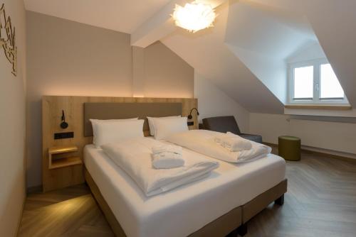 a bedroom with a large bed with white sheets at BERGlässig Hotel Bodenmais - 360 Grad Urlaub in Bodenmais