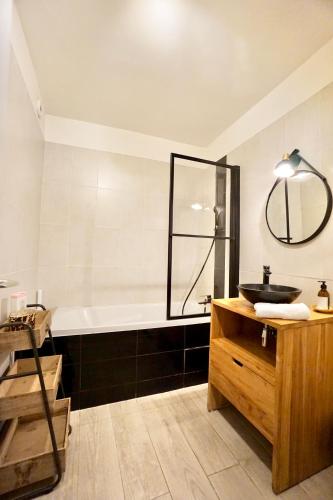 une salle de bain avec une baignoire, un lavabo et un miroir dans l'établissement L'authentique, à Concarneau