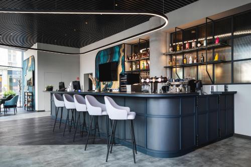 a bar with white bar stools in a restaurant at Focus Hotel Premium Wrocław in Wrocław