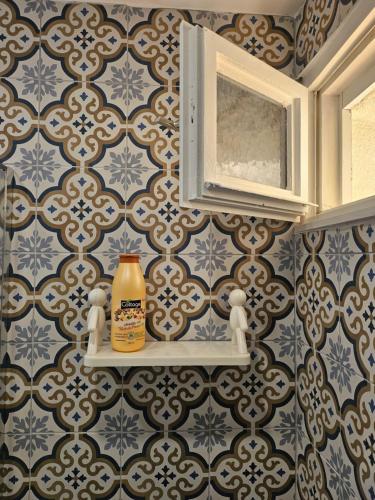 a bathroom with blue and white wallpaper and a shelf with a bottle at La Cabane vue mer et port in Cap d'Agde