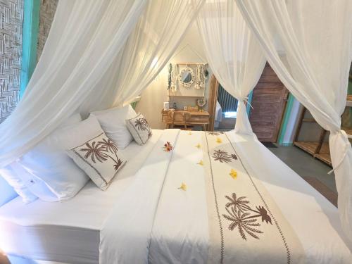 a bedroom with a white canopy bed with pillows at Secret Triangle in Toyapakeh