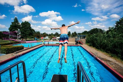 a man jumping off the side of a swimming pool at Chalet met hottub & omheinde tuin Zeeland VP090 in Heinkensand