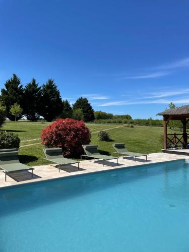 une grande piscine avec des chaises et un gazebo dans l'établissement les gîtes de la fabrique, à Villeneuve-de-Duras