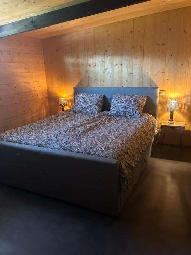 a bedroom with a large bed with a wooden wall at Onder de hanebalken in Dirkshorn
