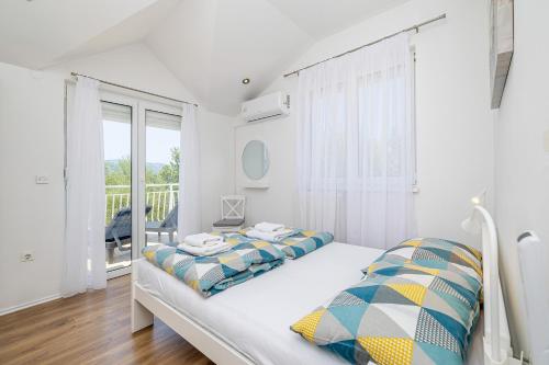 a white bedroom with a bed and a balcony at Holiday Home OLIVE GARDEN in Brzac