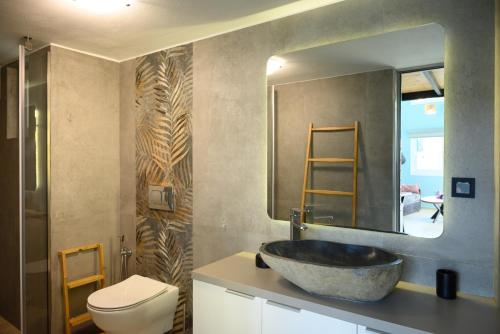 a bathroom with a sink and a toilet and a mirror at Cestrum Suites in Agios Nikolaos