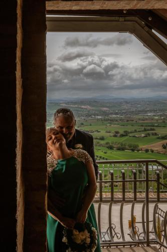 a bride and groom hugging in front of a window at La Luma Hotel in Montecosaro