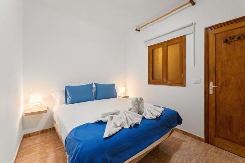 a bedroom with a bed with blue and white sheets at Home2Book Relaxing Órzola Getaway with BBQ in Orzola