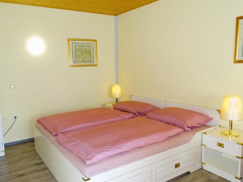 una camera da letto con un letto con lenzuola rosa e due lampade di Kölp - Gentz H a Kölpinsee auf Usedom