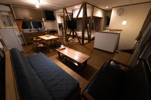 a living room with a couch and a table and a kitchen at ふらのの丘 in Kami-furano