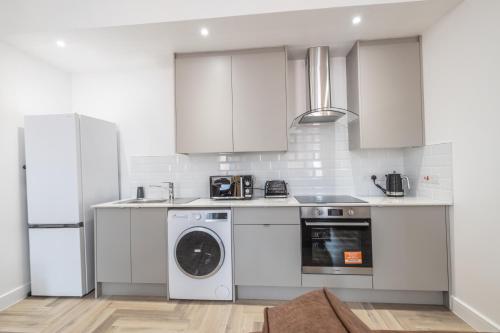 a kitchen with white cabinets and a washer at Luxury 2 Bed Apartment In The City Centre With Free Gym By The Pocklington - The Ceremonial Suite in Leicester