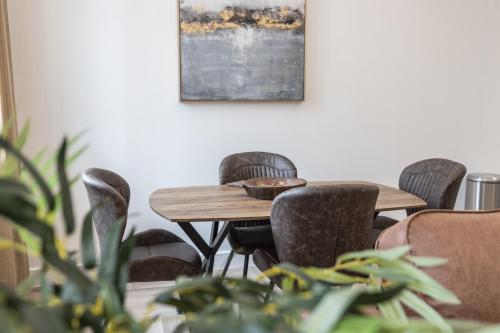 a wooden table with chairs and a painting on the wall at Luxury 2 Bed Apartment In The City Centre With Free Gym By The Pocklington - The Ceremonial Suite in Leicester