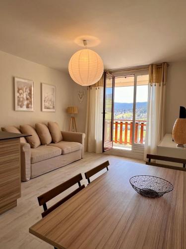 a living room with a couch and a large window at Le Balcon de Corrençon - Les Moucherolles in Corrençon-en-Vercors