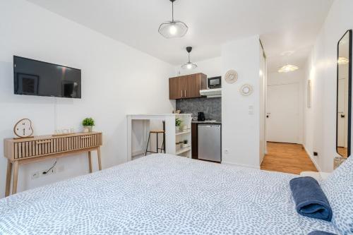 une chambre blanche avec un lit et une cuisine dans l'établissement Le Moana, 2pers 5min Disneyland Paris, à Montévrain