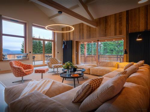 a living room with a couch and chairs and windows at Chalet La Parenthèse - OVO Network in Samoëns