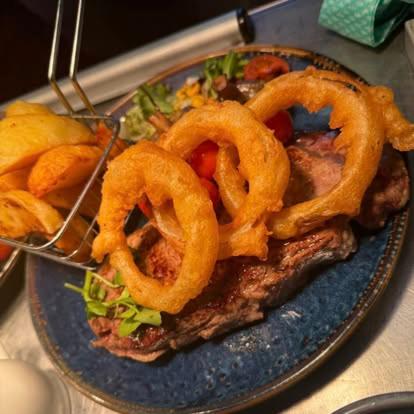 a plate of food with onion rings on a table at The Star Inn Weaverthorpe in Weaverthorpe