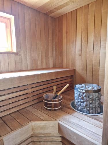 a sauna with a basket of logs and a bowl of rocks at Small house with sauna in Papsaare