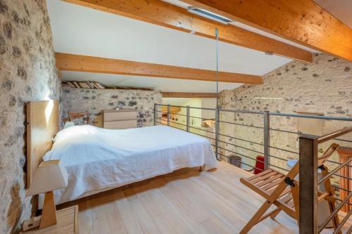 une chambre avec un lit blanc et un mur en pierre dans l'établissement Les Petites Écuries, à Gavaudun