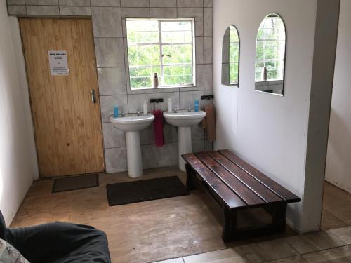 a bathroom with two sinks and a wooden bench at Sani Lodge & Cottages in Sani Pass