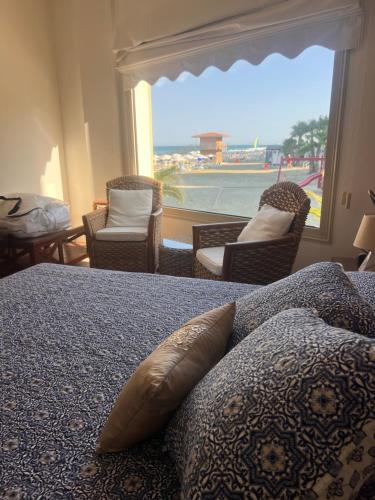 a bedroom with a bed with a window and chairs at Sandy Kisses in Larnaka