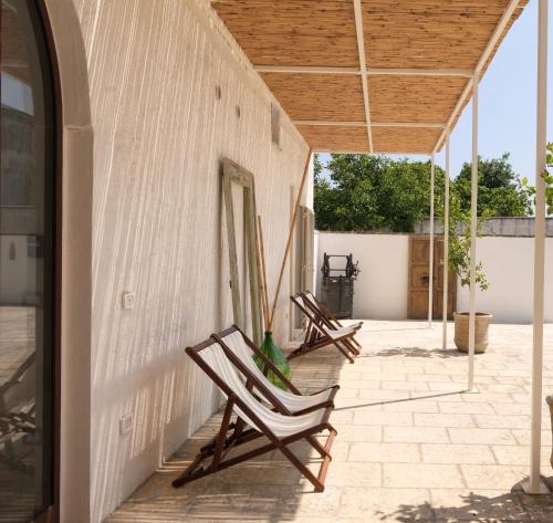 two rocking chairs on a patio with a building at Masseria Kalandini in Corigliano dʼOtranto