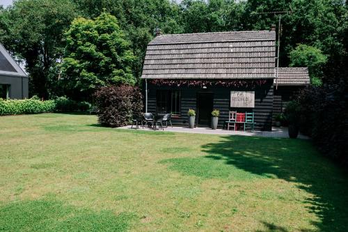a log cabin with chairs and a sign in a yard at Bosserheide in Well