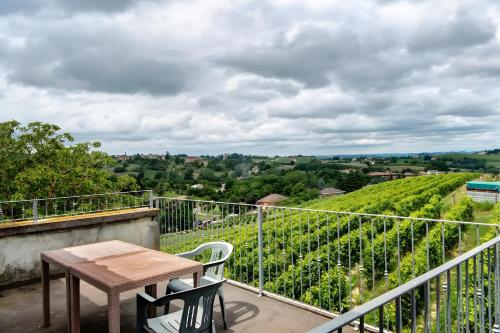 a table and chair on a balcony with a view of a vineyard at Cascina Orlandi in Costigliole dʼAsti
