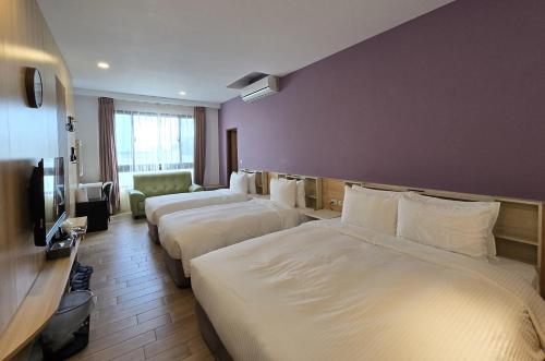 a hotel room with three beds and a tv at Lukang Holiday Hostel in Lugang