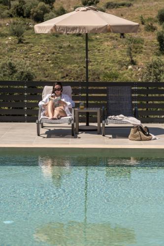 a man sitting in a chair with a dog next to a pool at Marea Luxury Suites in Koríthion