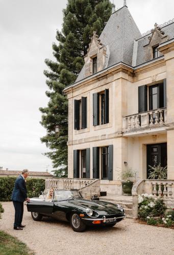 un homme debout à côté d'une voiture noire devant une maison dans l'établissement Château Lacoste Pujols near Saint Emilion, à Pujols Gironde