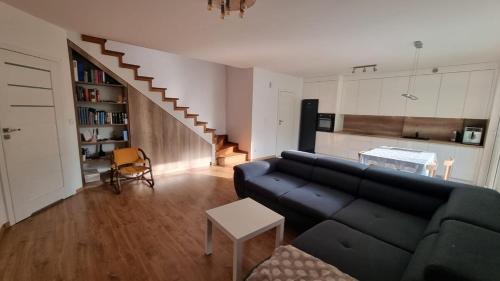 een woonkamer met een blauwe bank en een keuken bij Apt blisko morza in Kosakowo