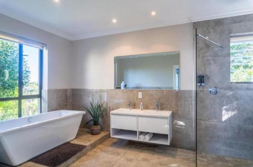 a bathroom with a tub and a sink and a mirror at Breakwaters Haven - Luxury Villa Pezula in Knysna