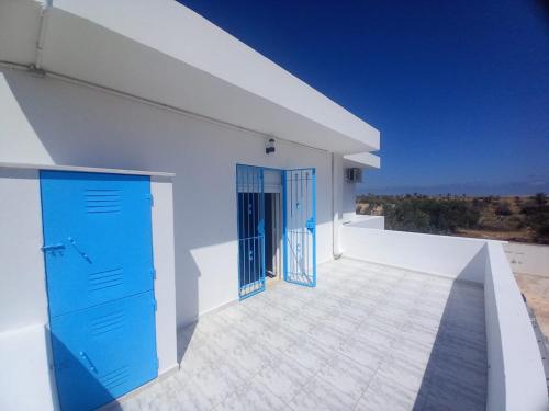 an open door on a white building with blue doors at Villa Selma in Bin Rhilouf