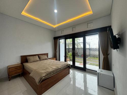 a bedroom with a bed and a large window at Kubu Taraya in Jimbaran