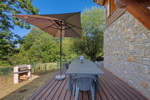 una mesa de picnic con una sombrilla en una terraza de madera en L'edliane, en Font-Romeu-Odeillo-Via