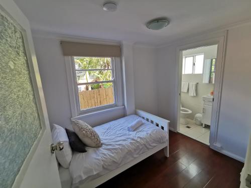 a small bedroom with a bed and a window at Spacious 5BD Garden House in Hornsby close 2 train in Hornsby